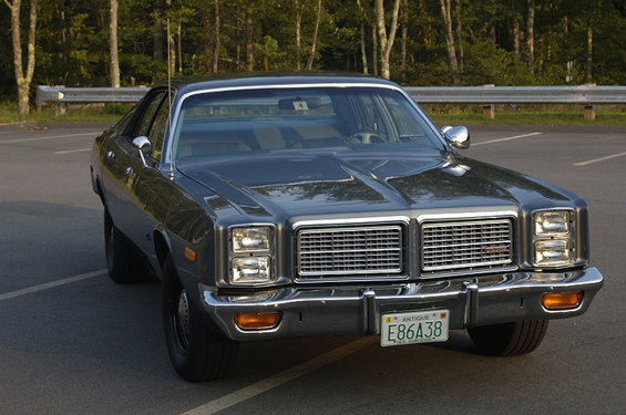 Front view of a dark sedan with a chrome grille and quad headlights. License plate reads E86A38