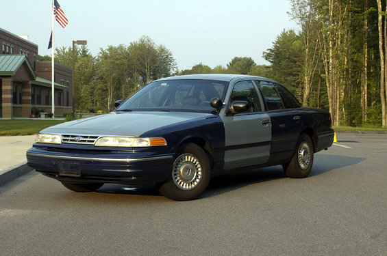 Two-tone blue and gray Ford Crown Victoria police car parked on asphalt