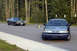 1978 Dodge Monaco - Two cars, a 1978 Dodge Monaco and a modern sedan, are parked on a paved road with trees in the background.
