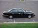 1998 Ford Crown Victoria - A black 1998 Ford Crown Victoria sedan is shown from the side in an empty parking lot.