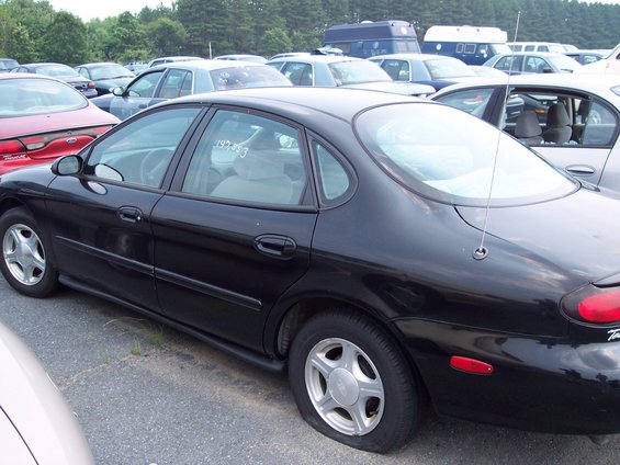 Black sedan with a flat tire parked in a lot with other cars