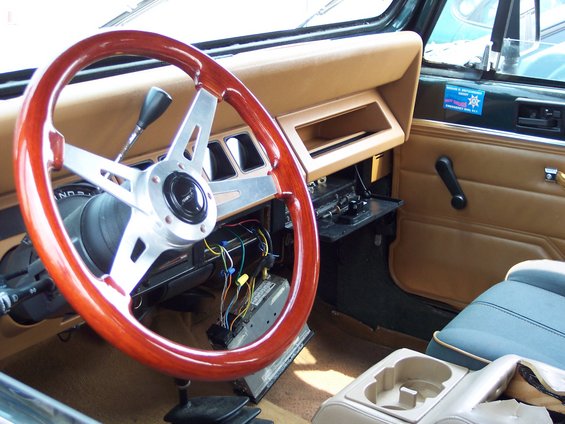 Aftermarket wood and chrome steering wheel in a Jeep's tan interior. Wires are visible under the dash