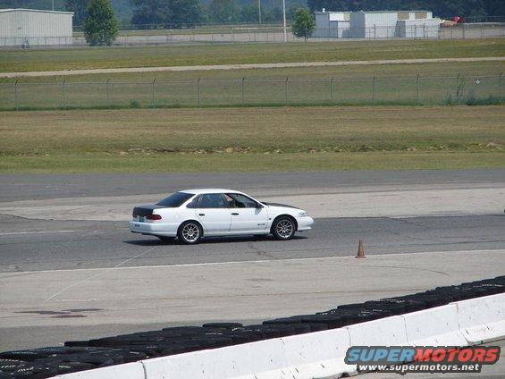 White 1992 Ford Taurus sedan with black hood and trunk on a race track