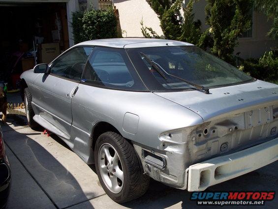 Silver coupe, looks like a 1993 Ford Probe, parked in a driveway with the rear bumper removed