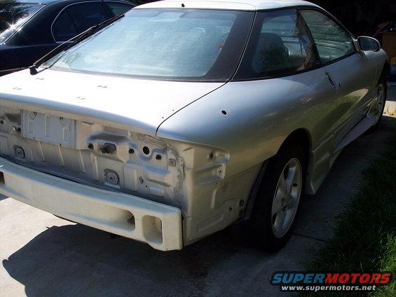White 1993 Ford Probe coupe, rear view, missing bumper and taillights, parked on asphalt