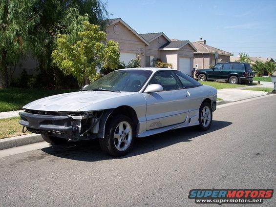 Silver 1993 Ford Probe with missing front bumper parked on street