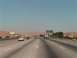 1971 Ford Bronco - Vehicles travel on a multi-lane highway under a clear sky, with a road sign indicating upcoming exits.