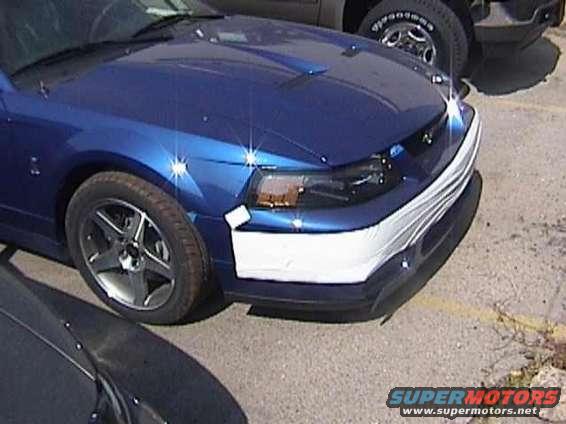 Blue Ford Mustang front fender and bumper with white cover. Another vehicle is partially visible