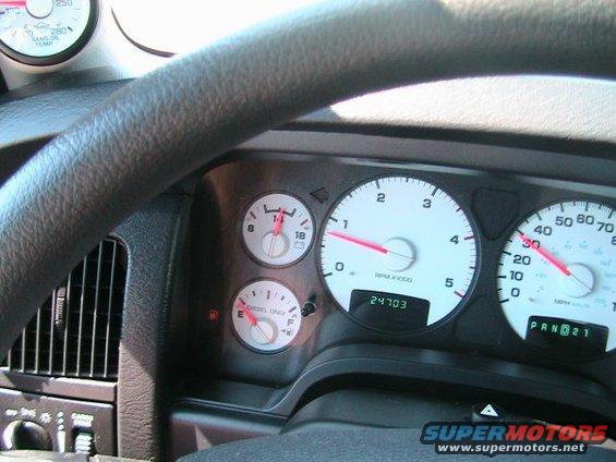 Dashboard with speedometer, tachometer, fuel gauge, and odometer showing 24703 miles