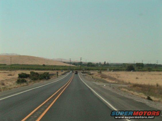 Highway scene with distant cars and dry landscape