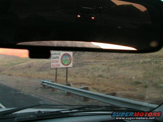 Interior view with 'DRIVE SAFE STAY ALIVE' sign reflected in rearview mirror
