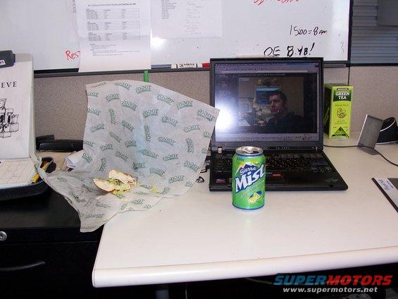 Desk with a half-eaten sandwich, a can of Sierra Mist, and a laptop displaying a video call
