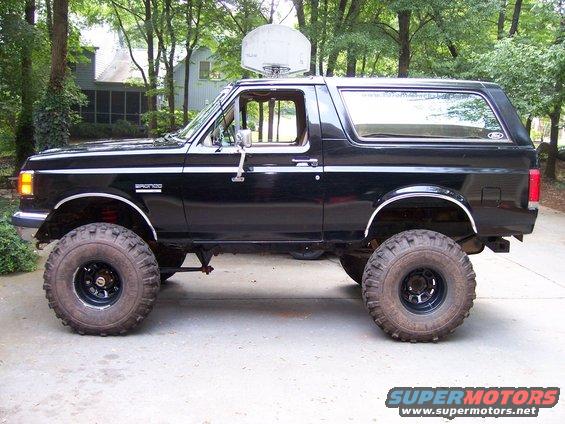 Black 1990 Ford Bronco lifted with large off-road tires, side view