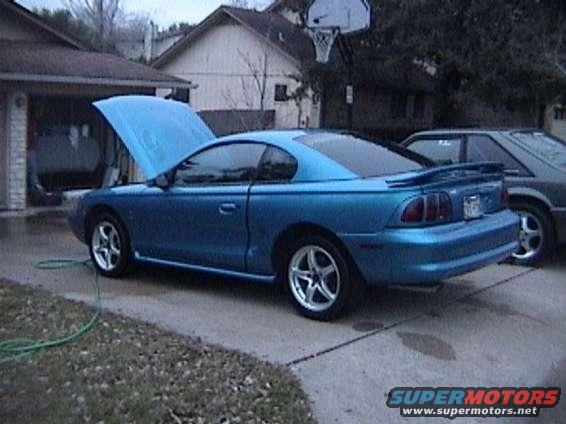 Blue Ford Mustang with hood open, parked on driveway next to another car