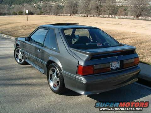1989 Ford Mustang coupe, rear 3/4 view, grey paint, aftermarket wheels, spoiler