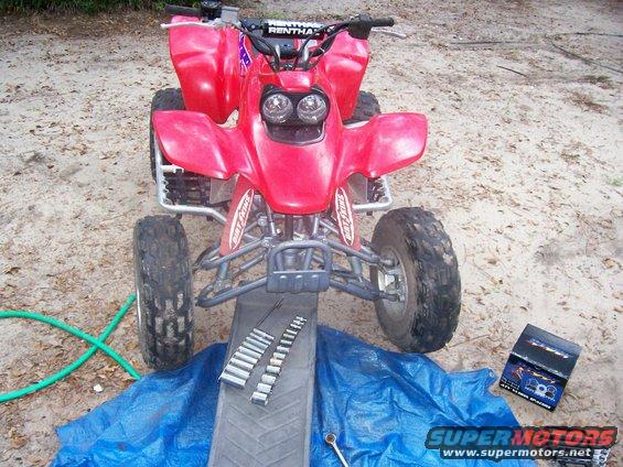 Red 2002 Honda 400 EX ATV on a ramp with tools, front view