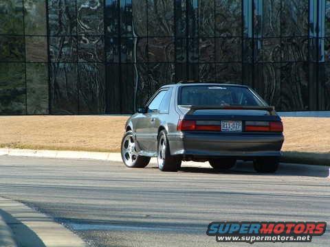 Gray 1989 Ford Mustang parked by a building with reflective windows