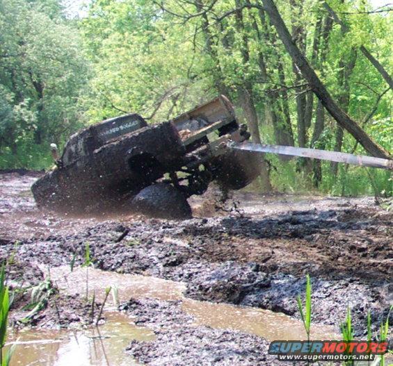 Muddy truck stuck in a bog, being pulled by a strap