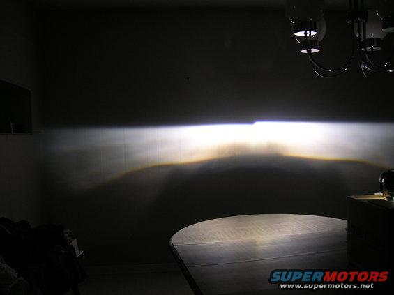 Headlight beam pattern projected onto a wall, with a table in the foreground