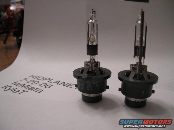 Two HID bulbs on a white surface with handwritten text and a SuperMotors logo