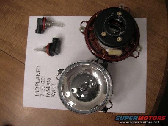 Two headlight bulbs and disassembled headlight assembly on paper with text