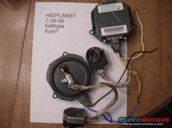 HID ballast, projector, and housing laid out on paper with text