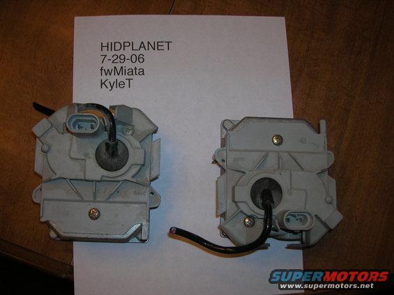 Two gray door lock actuators with black wires on a white paper