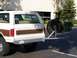 1988 Ford C-350 (Centurion Conversions) - This Ford Bronco, likely from the 1980s, has a rear-mounted spare tire and a cargo rack with green containers.