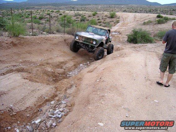 Green and camouflage Ford Bronco climbing a dirt hill
