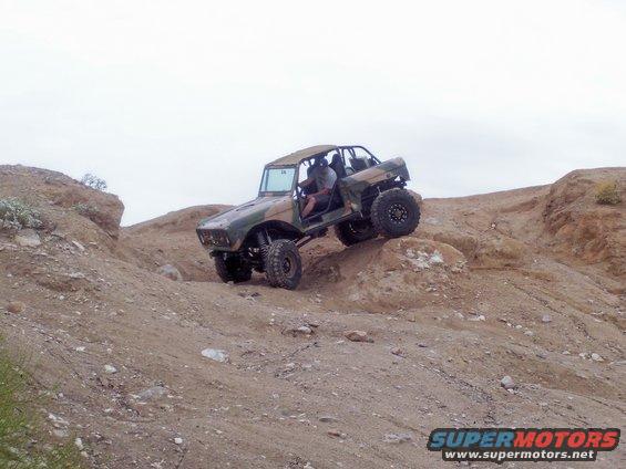 Custom off-road vehicle with camouflage paint climbing a rocky hill