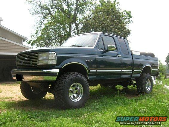Dark green 1994 Ford F-150 pickup truck with chrome accents and large tires, parked on grass