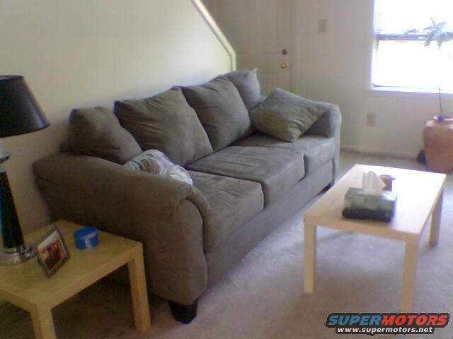Living room with a couch, coffee table, end table, lamp, and a window