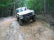 1992 Ford Mustang - A white Ford Bronco navigates a challenging rocky terrain on a wooded trail.
