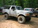 1992 Ford Mustang - A lifted Ford Bronco is parked on a dirt trail surrounded by trees, with other vehicles present.