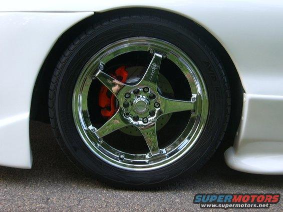 Chrome five-spoke wheels with orange brake calipers on a white car
