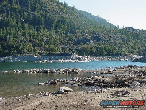 Water and rocky shore with forested mountain backdrop