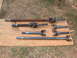 1994 Jeep YJ - Several driveshafts and U-joints are displayed on a wooden plank outdoors.