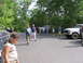 1995 Ford C-350 (Centurion Conversions) - A white Ford F-Series truck is parked in a wooded area alongside other vehicles and people.