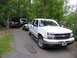 1995 Ford C-350 (Centurion Conversions) - A white pickup truck is parked on a paved path, towing a trailer with an ATV. Another pickup is behind it.