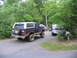 1995 Ford C-350 (Centurion Conversions) - Two trucks are parked at a campsite with tents in the background.