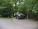 1995 Ford C-350 (Centurion Conversions) - A modified 1995 Ford Bronco is parked on a paved road surrounded by trees, with another vehicle behind it.