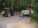 1995 Ford C-350 (Centurion Conversions) - Two vehicles, a Jeep and a Ford pickup, are parked on a road in a wooded area with a blue storage bin nearby.