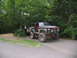 1995 Ford C-350 (Centurion Conversions) - Modified 1978 Ford Bronco with off-road modifications, parked beside a black SUV in a wooded area.