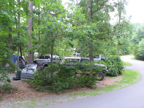 Dark blue pickup truck with white camper shell parked in a wooded area