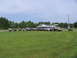 1995 Ford C-350 (Centurion Conversions) - A group of off-road vehicles are parked in a field by a gas station.