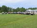 1995 Ford C-350 (Centurion Conversions) - Several trucks and SUVs are parked in a grassy field on a sunny day.