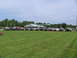 1995 Ford C-350 (Centurion Conversions) - A collection of modified trucks and SUVs are gathered in a grassy field near a gas station.