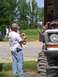 1995 Ford C-350 (Centurion Conversions) - Man works on a large truck with oversized tires in an outdoor setting.