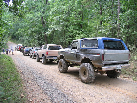 Gray and blue Ford Bronco with large tires on a gravel road