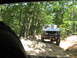 1995 Ford C-350 (Centurion Conversions) - Silver Ford F-Series truck navigates a challenging, rocky off-road trail through a dense forest.